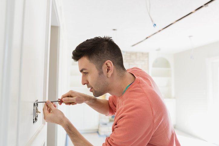 Polk Electric LLC | Young man installing light switch at home