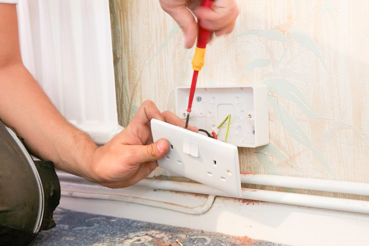 Polk Electric LLC | Electrician wiring a new power socket in a residential property.